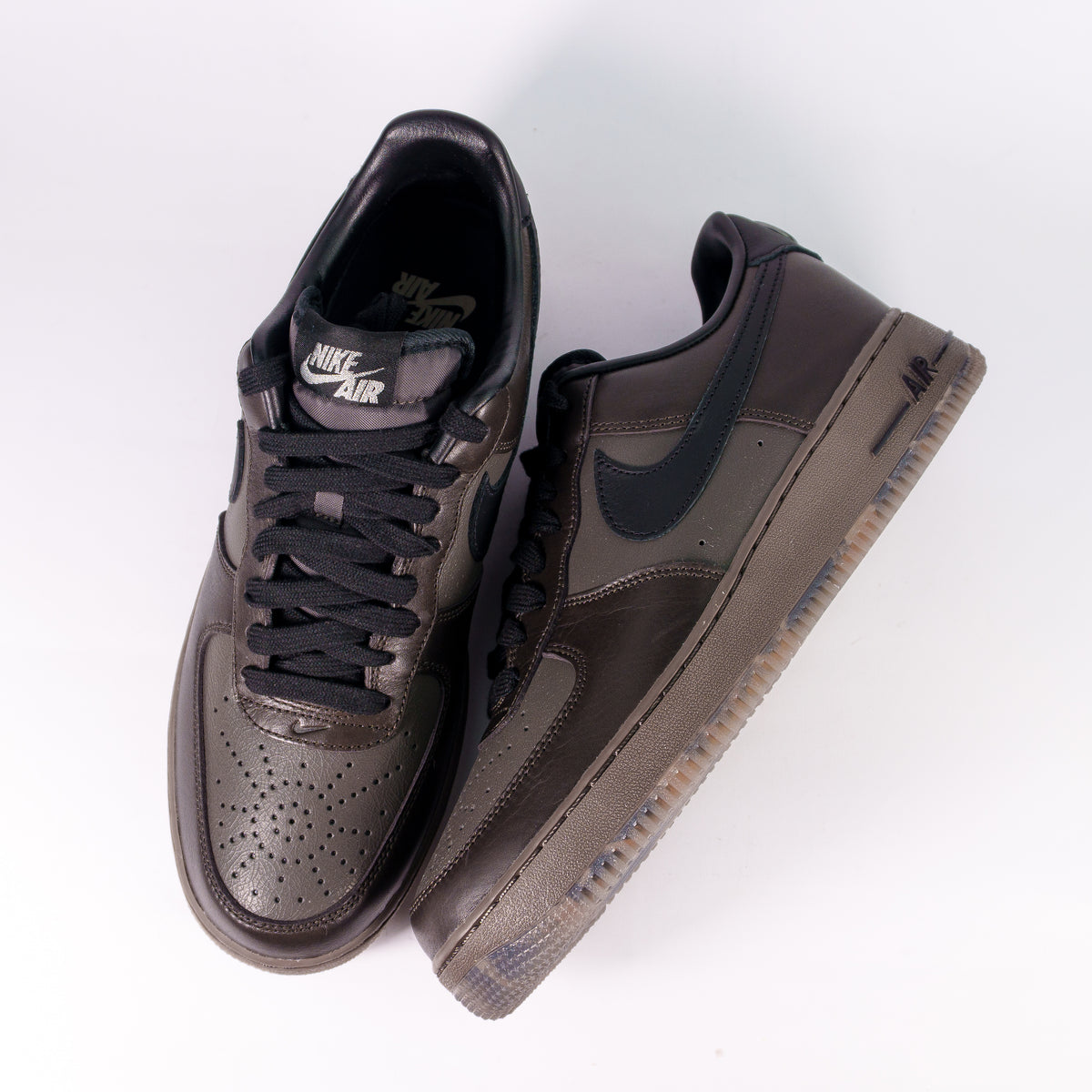 Пара Nike Air Force 1 Low коричневі згори: перфорований носок, чорні шнурки і лейбл Nike Air на язичку