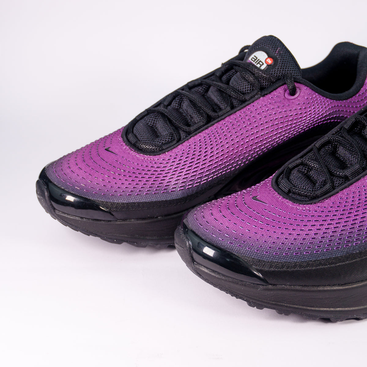 Носки Nike Air Max DN SE з фіолетового текстильного верху та чорного гумового бампера зблизька