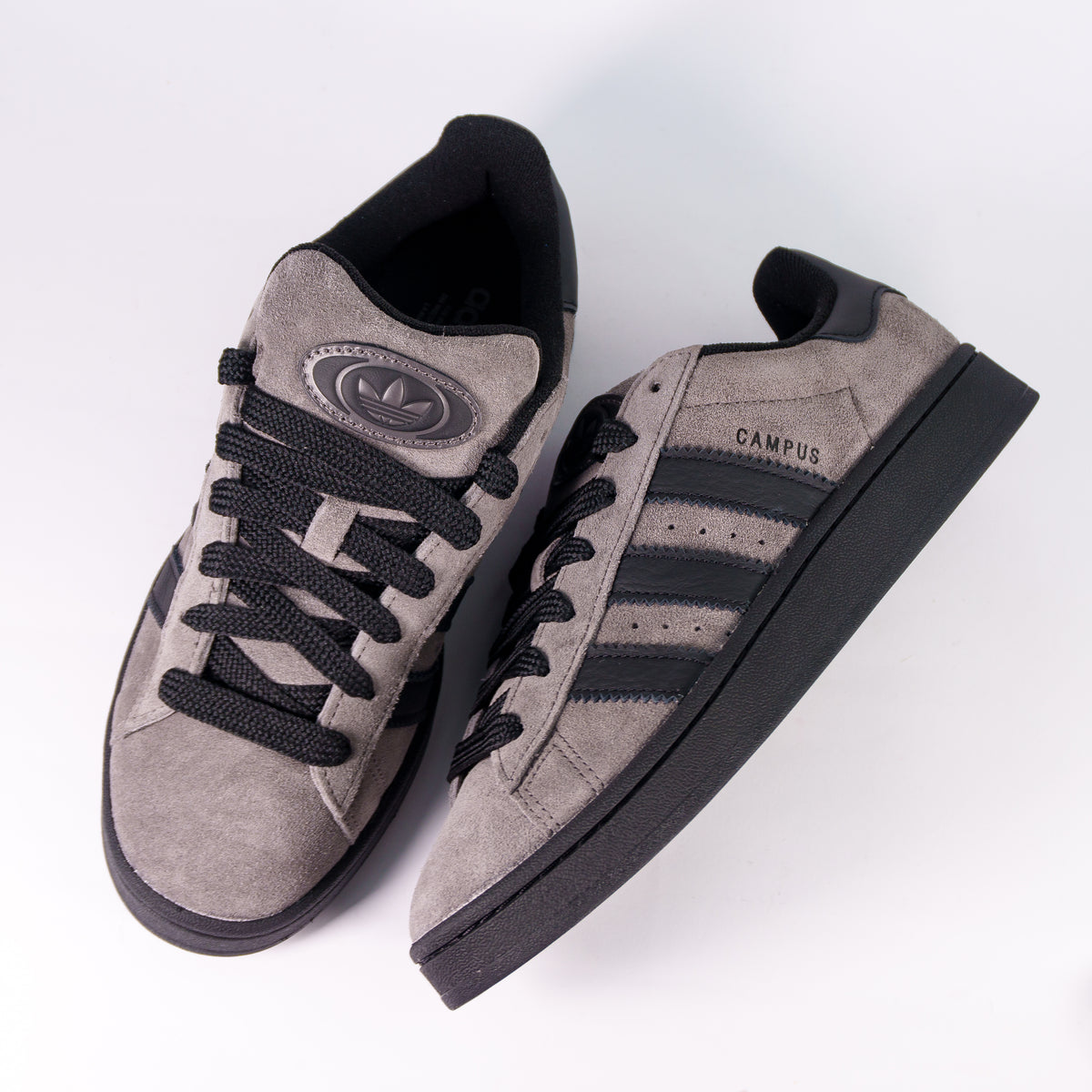 Пара Adidas Campus 00s Charcoal згори: широкі чорні шнурки і нашивка з трилисником на язичку