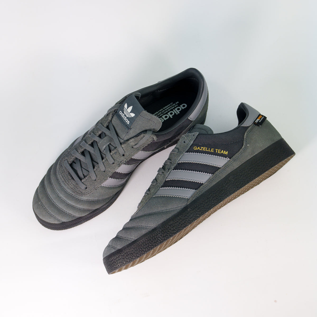 Пара Adidas Gazelle Team Cordura сірі згори: замшевий носок, сірі шнурки і золотий напис Gazelle Team