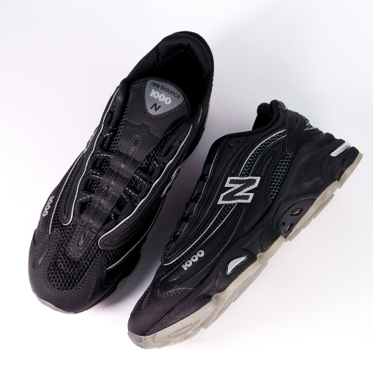 Пара New Balance 1000 Black Lunar Pack згори: чорна сітка, срібний кант і лейбл 1000 на язичку