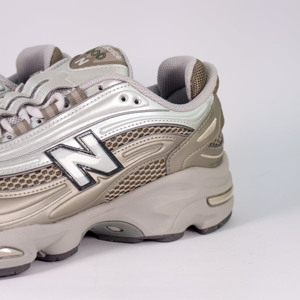 Боковина New Balance 1000 Light Silver Metallic зблизька: срібна N і шестикутна сітка