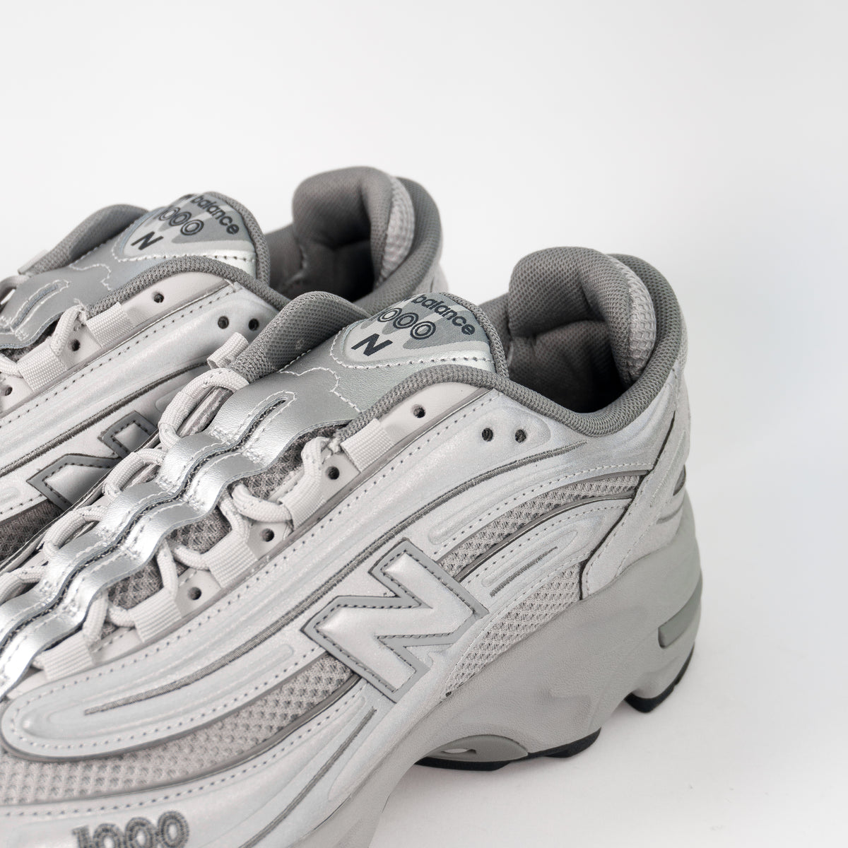 Шнурівка і боковина New Balance 1000 Reflective Pack зблизька: світловідбивні накладки та сіра N