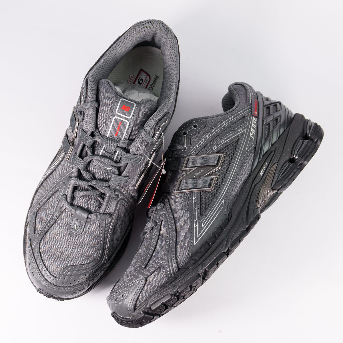 Пара New Balance 1906R Grey Castlerock згори: сірі шнурки і червона нашивка на язичку