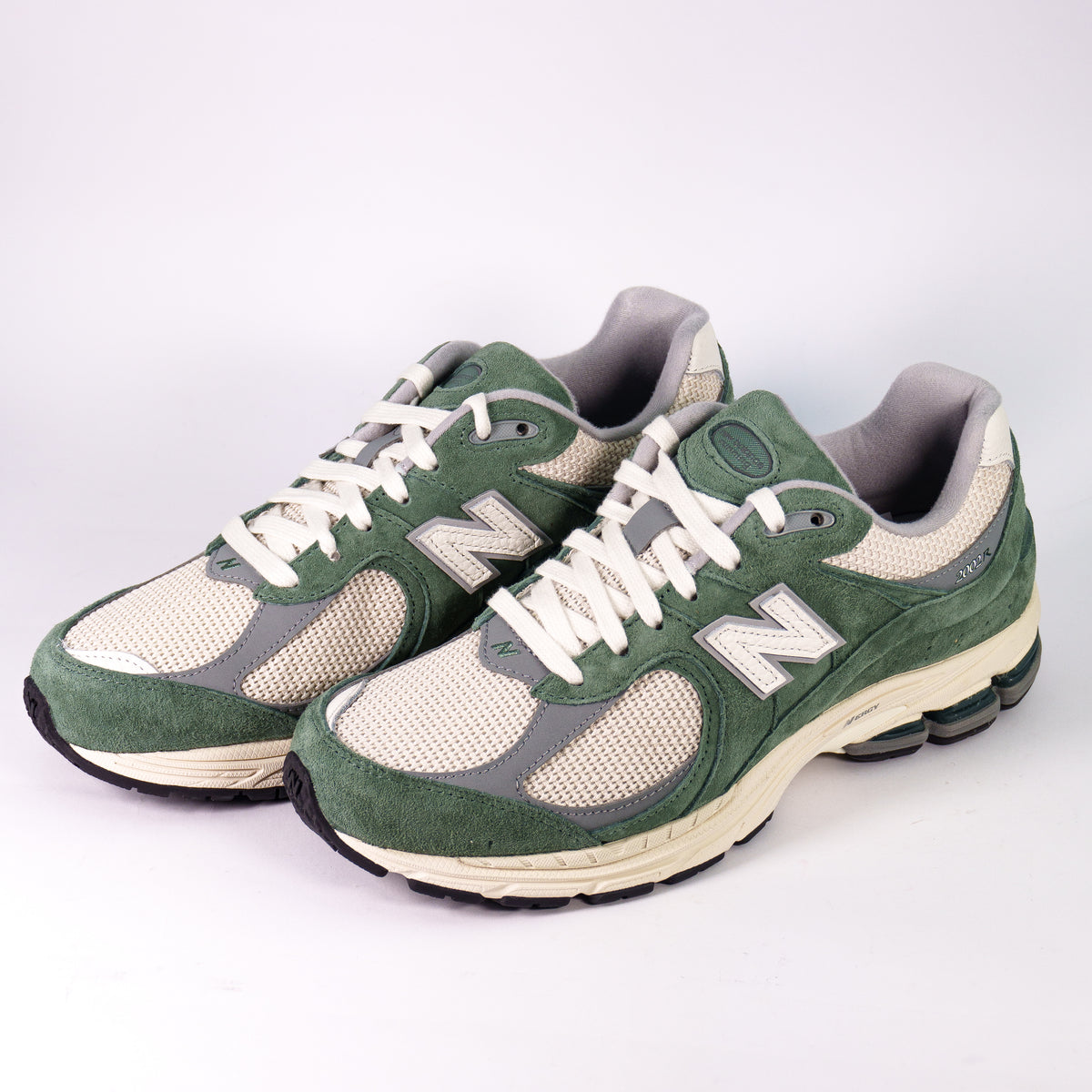 Пара кросівок New Balance 2002R Green White на кремовій підошві — ракурс три чверті спереду